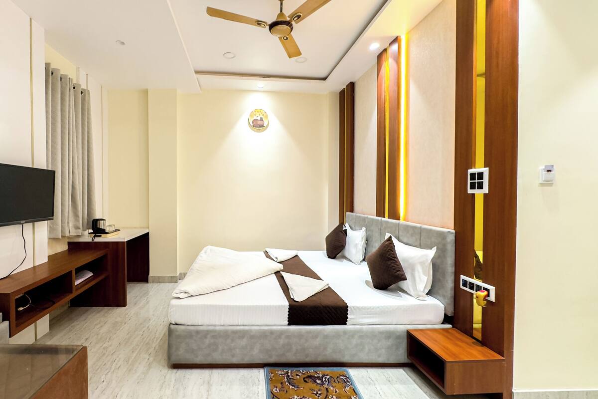 A modern bedroom with a bed, TV, and a ceiling fan.