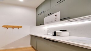 A modern kitchen with white countertops, grey cabinets, and a microwave.
