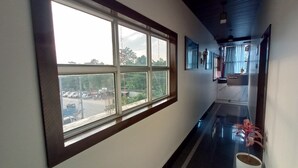 A hallway with a large window, a reception desk, and a potted plant. - Hotel Blue Bird (North Lakhimpur)
