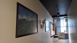 A reception area with a large framed landscape painting, a wall-mounted light fixture, and a reception desk with a 'Manager' sign. - Hotel Blue Bird (North Lakhimpur)