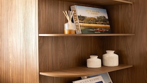 Una estantería de madera con un libro titulado 'PARIS CHIC' y dos jarrones de cerámica blanca.