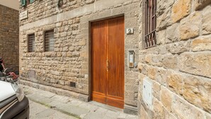 A stone building with a wooden door and a number '2' sign. - Mamo Florence - Santo Stefano Apartment (Florence)