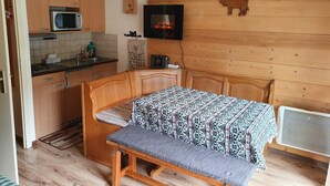 A compact kitchen with wooden cabinets, a microwave, and a small dining area with a bench and table. - Studio 4 persons Châtel / Linga. Chairlift within walking distance. (Châtel)
