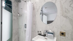 A modern bathroom with a shower, a sink, and a mirror.