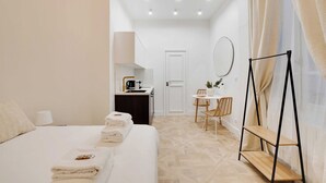 A hotel room with a bed, a desk, a chair, and a small table.
