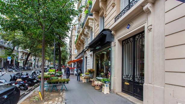 A street with parked cars and a flower shop.
