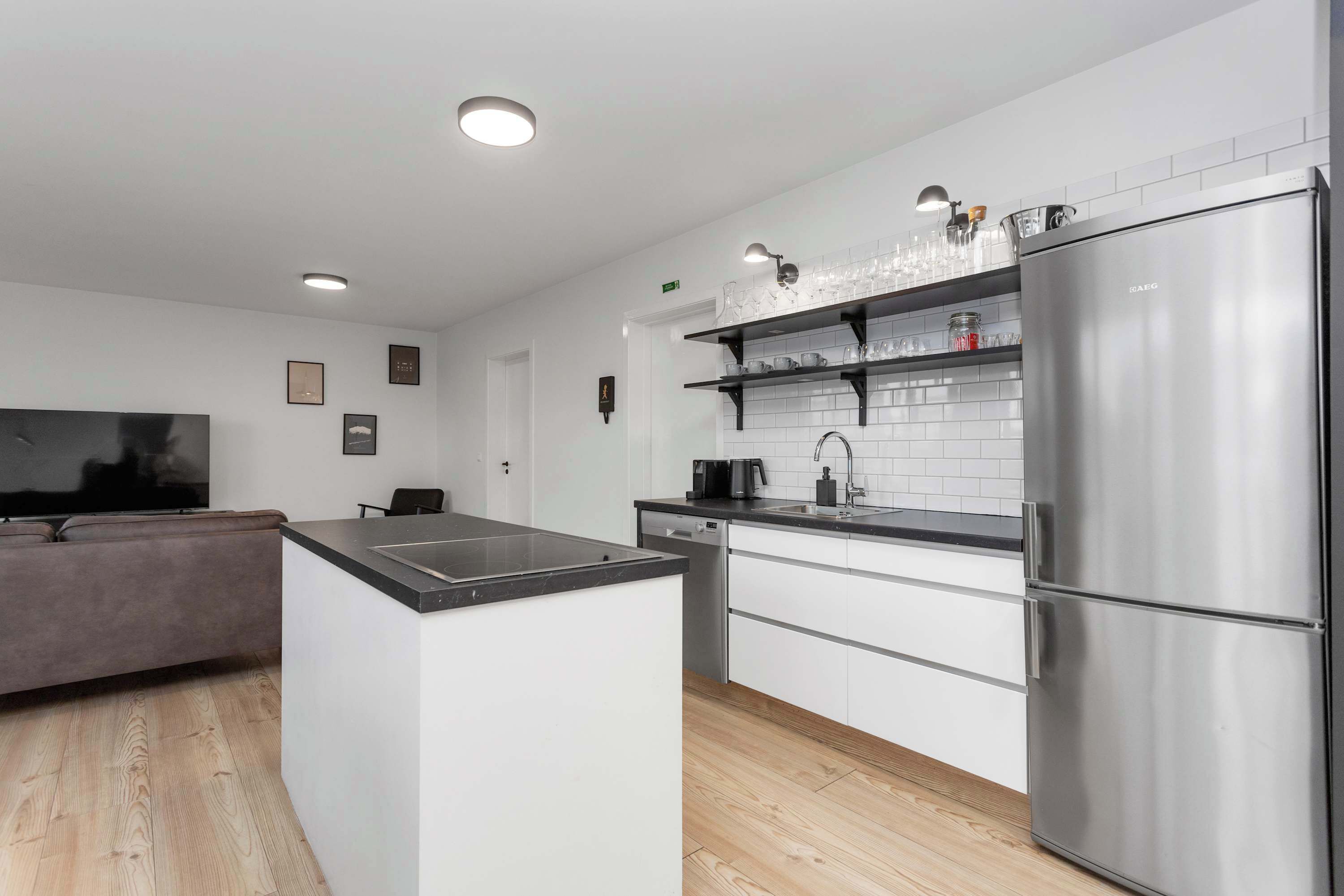 Een moderne keuken met witte kasten, een roestvrijstalen koelkast en een zwart aanrecht.