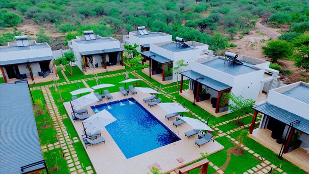 A modern resort with a central swimming pool surrounded by lounge areas and outdoor seating. - Solai Oasis (Namanga)