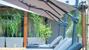 A poolside area with lounge chairs and a canopy. - Solai Oasis (Namanga)