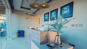 A modern reception area with a counter, framed artwork, and a vase with flowers. - Solai Oasis (Namanga)