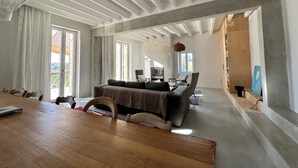 Ein geräumiger Wohnbereich mit Esstisch aus Holz, einer Couch und einem Fernseher.