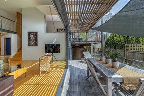 A modern outdoor dining area with a wooden deck, a pergola providing shade, and a view of the backyard. - Luxury Eco Villa, Hout Bay, Cape Town,south Africa (Cape Town)