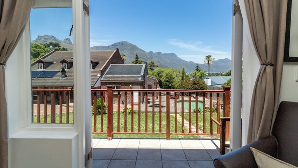 A balcony with a view of mountains, a pool, and a wooden deck. - Room in Guest Room - Garden Cottage, Houtbay, Cape Town, South Africa (Cape Town)