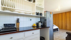 A compact kitchen with white cabinets, a black countertop, and a stainless steel refrigerator. - Room in Guest Room - Garden Cottage, Houtbay, Cape Town, South Africa (Cape Town)