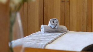 A wooden-paneled room with a bed, a towel, and a vase with flowers. - Room in Guest Room - Garden Cottage, Houtbay, Cape Town, South Africa (Cape Town)