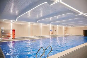 Une piscine intérieure à l’eau claire, entourée de murs dotés d’un éclairage encastré.