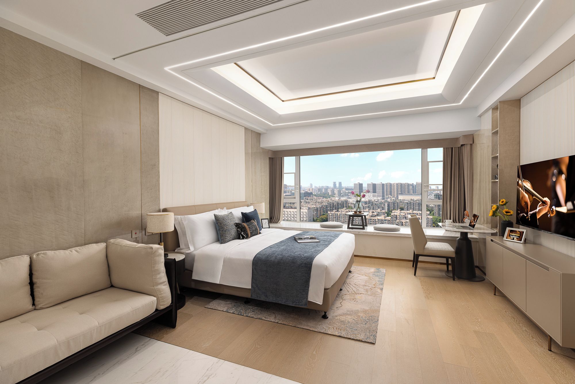 A modern hotel room with a large bed, a sofa, a desk with a chair, and a TV.