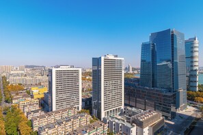 Un immeuble de grande hauteur doté d’une façade moderne en verre, entouré d’autres bâtiments et surplombant un ciel dégagé.