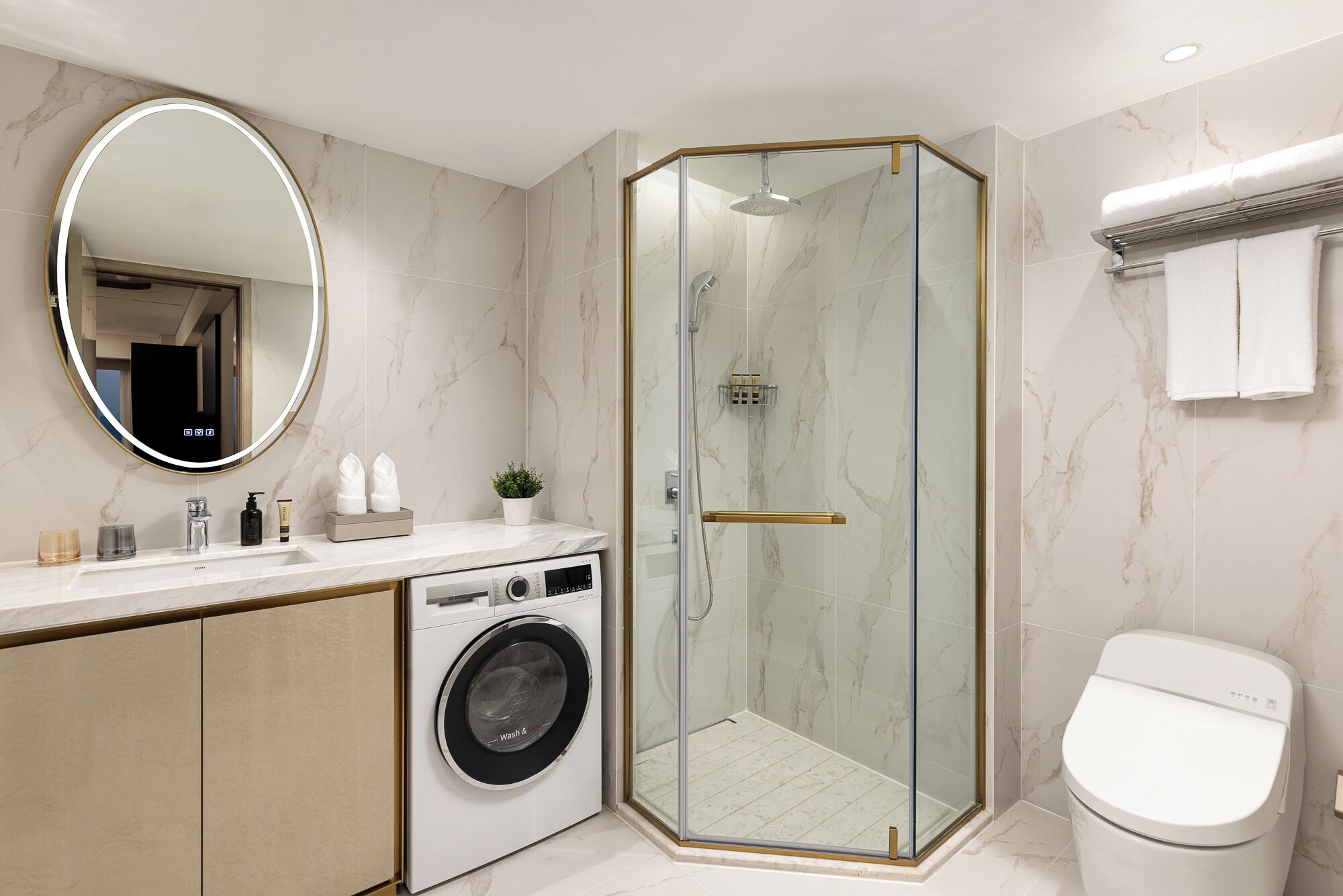 Ein modernes Badezimmer mit einer Duschkabine, einer integrierten Waschmaschine und einer Toilette.