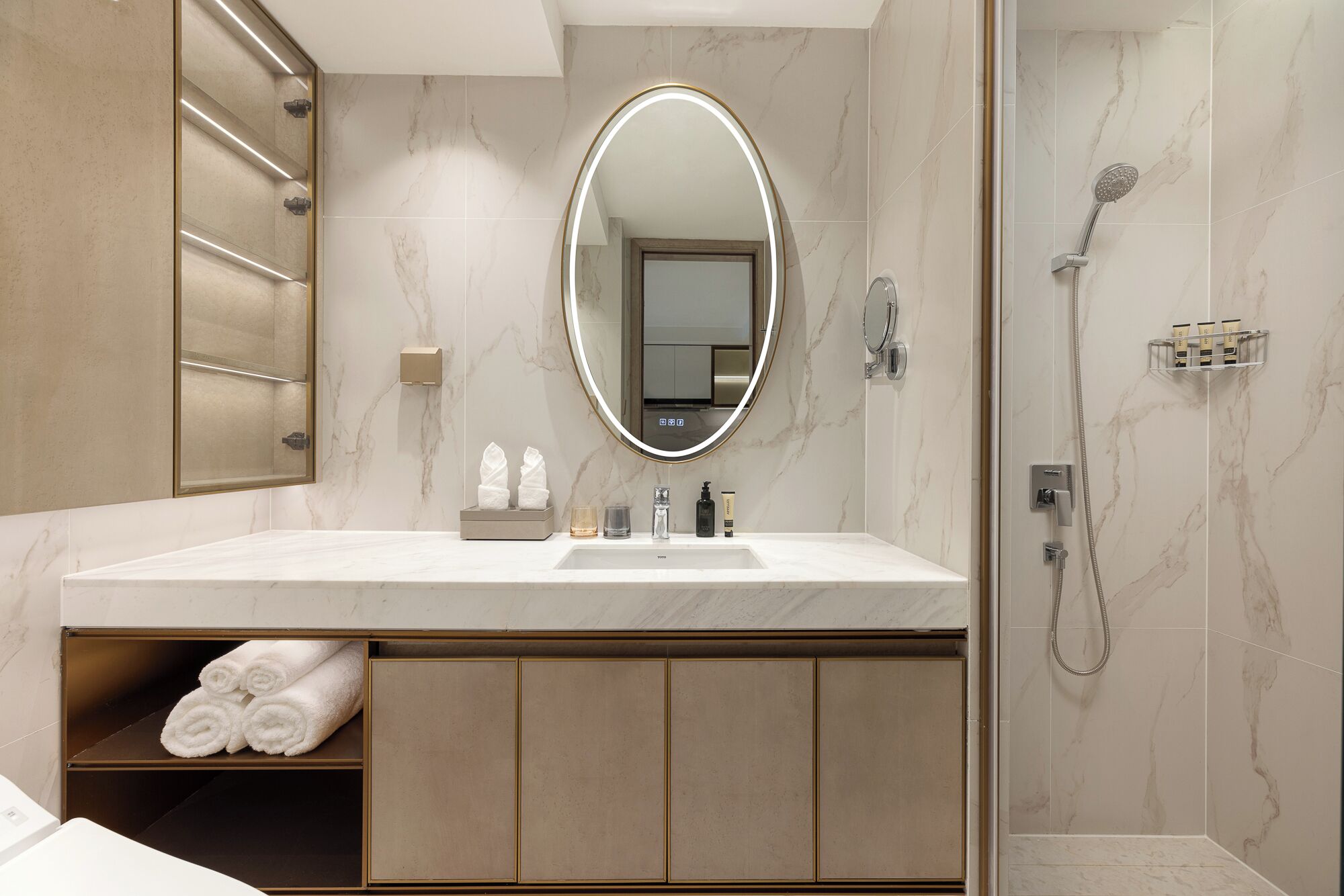 Un baño moderno con tocador de mármol, un espejo grande, ducha y perchero.