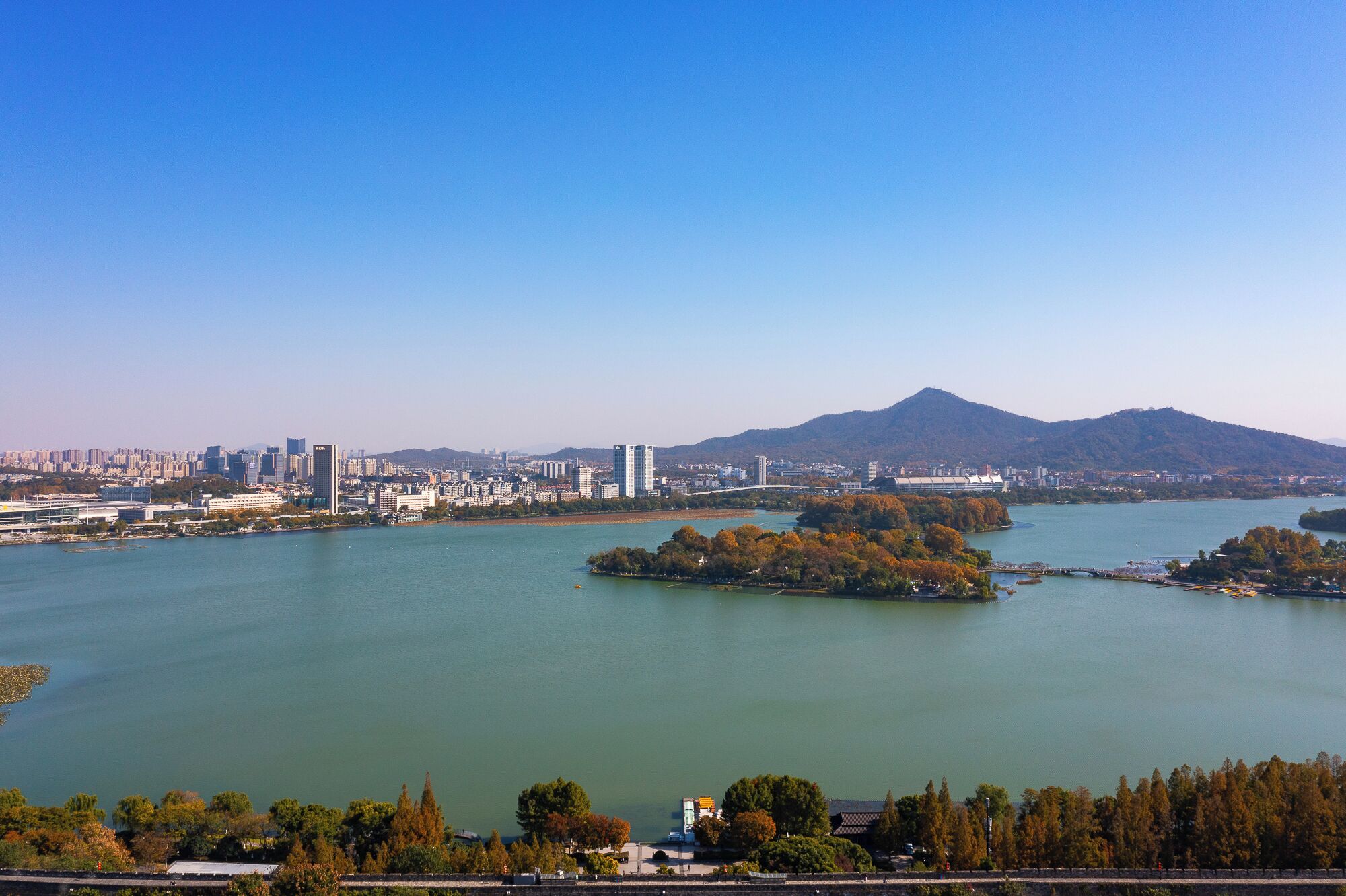 Un paisaje urbano con un río, un puente y una montaña al fondo.