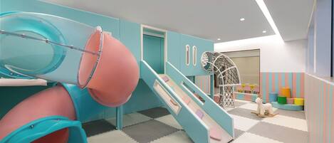Zona de juegos infantiles con toboganes y una red de escalada.