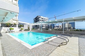 A rooftop pool with clear blue water, surrounded by lounge chairs and potted plants. - 1 Bedroom Apartment, Seapoint, Cape Town (Cape Town)