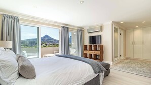 Une chambre avec un grand lit, une télévision, une armoire et une vue sur la montagne.