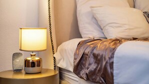 A neatly made bed with white linens and a brown blanket, a bedside lamp with a gold base, and a small decorative item on the nightstand. - Charming Garden Cottage, Campsbay, Cape Town (Cape Town)