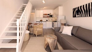 A modern living space with a staircase, a dining area, a kitchen, and a sofa.