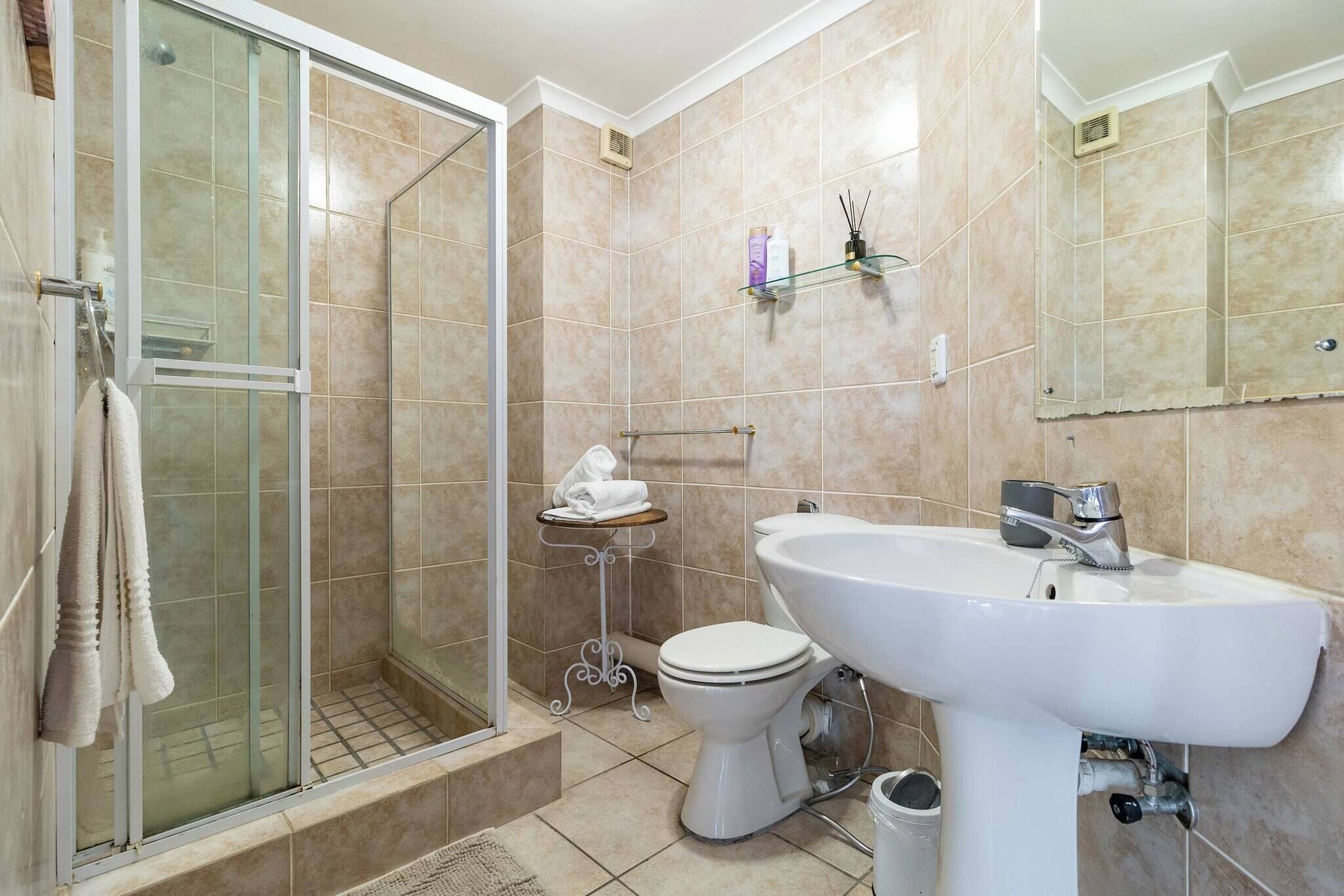 Un bagno con doccia vetro, un water e un lavandino.