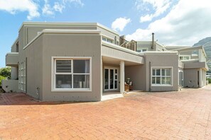 A modern two-story house with a flat roof, large windows, and a paved driveway. - Beachfront Villa Sea Breeze, Hout Bay, Cape Town (Cape Town)