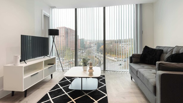 Een moderne woonkamer met een grote televisie, een bank en een salontafel.