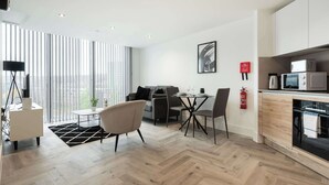 Een modern appartement met een eethoek, keuken en grote ramen.