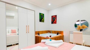 Une chambre d’hôtel avec un lit, une coiffeuse avec un miroir, un lavabo et une petite fenêtre.