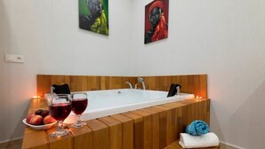 Une salle de bain moderne avec un meuble-lavabo en bois, une baignoire et deux œuvres d’art encadrées accrochées au mur.