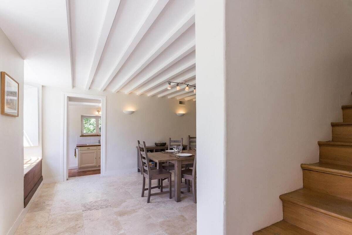 Un couloir étroit mène à une salle à manger, avec un escalier en bois sur le côté droit.