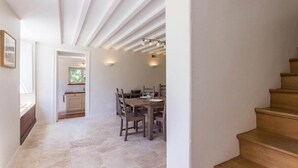 A narrow hallway leading to a dining area with a wooden staircase on the right. - The gardener's house (Tracy-sur-Mer)