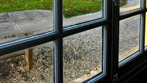 A view through a window with a clear sky, a grassy area, and trees. - The gardener's house (Tracy-sur-Mer)