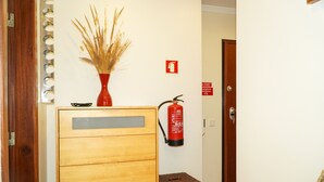 A wooden cabinet with a vase of dried plants, a fire extinguisher, and a small wicker basket. - Sacada Apartment - Great Balcony (Guia)