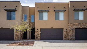 A modern multi-story residential building with a flat roof, large windows, and a stone accent wall.