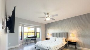 A bedroom with a bed, a ceiling fan, a desk with a chair, and a window. - Welcome to Your Luxurious Golf Getaway! (Fort Myers)