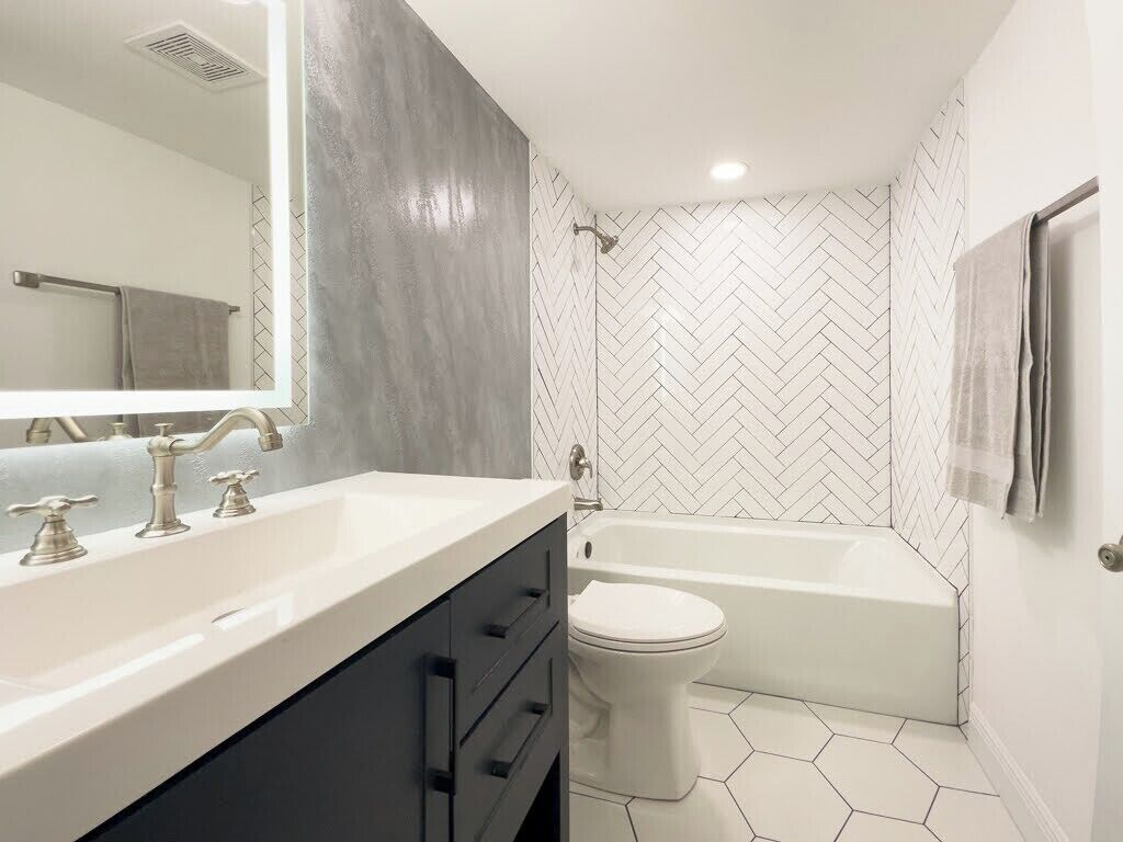A modern bathroom with a white sink, vanity, and a freestanding bathtub.