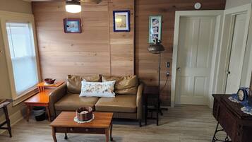 Una sala de estar acogedora con un sofá de cuero marrón, una mesa de centro de madera y piso de madera.