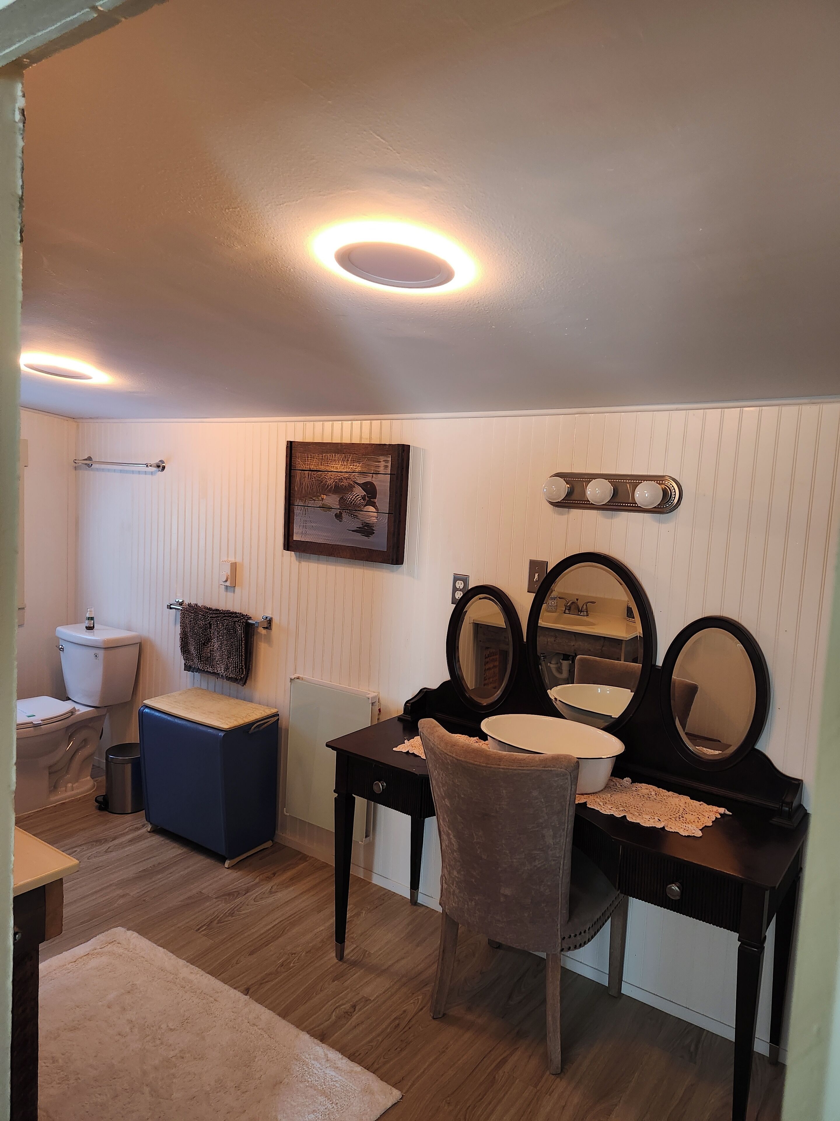 Un baño con inodoro, bidé, tocador con espejos y un perchero para toallas.
