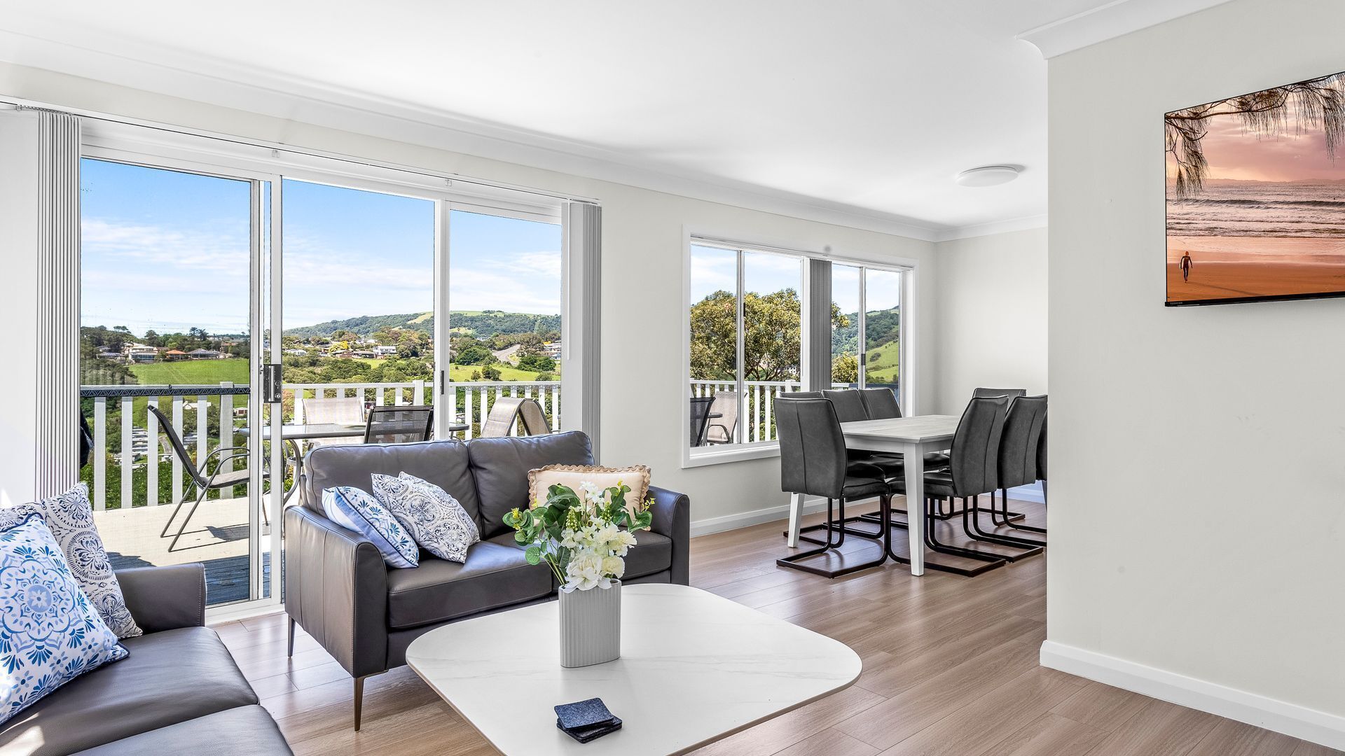 A spacious living room with a balcony, large windows, and a dining area.