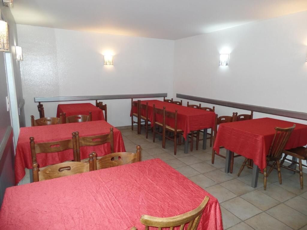 Uma sala de jantar com várias mesas e cadeiras, cada uma coberta por uma toalha vermelha.