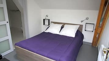 A bedroom with a bed, a nightstand, and a wall-mounted lamp.