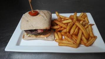 A sandwich with a toothpick and a plate of French fries.