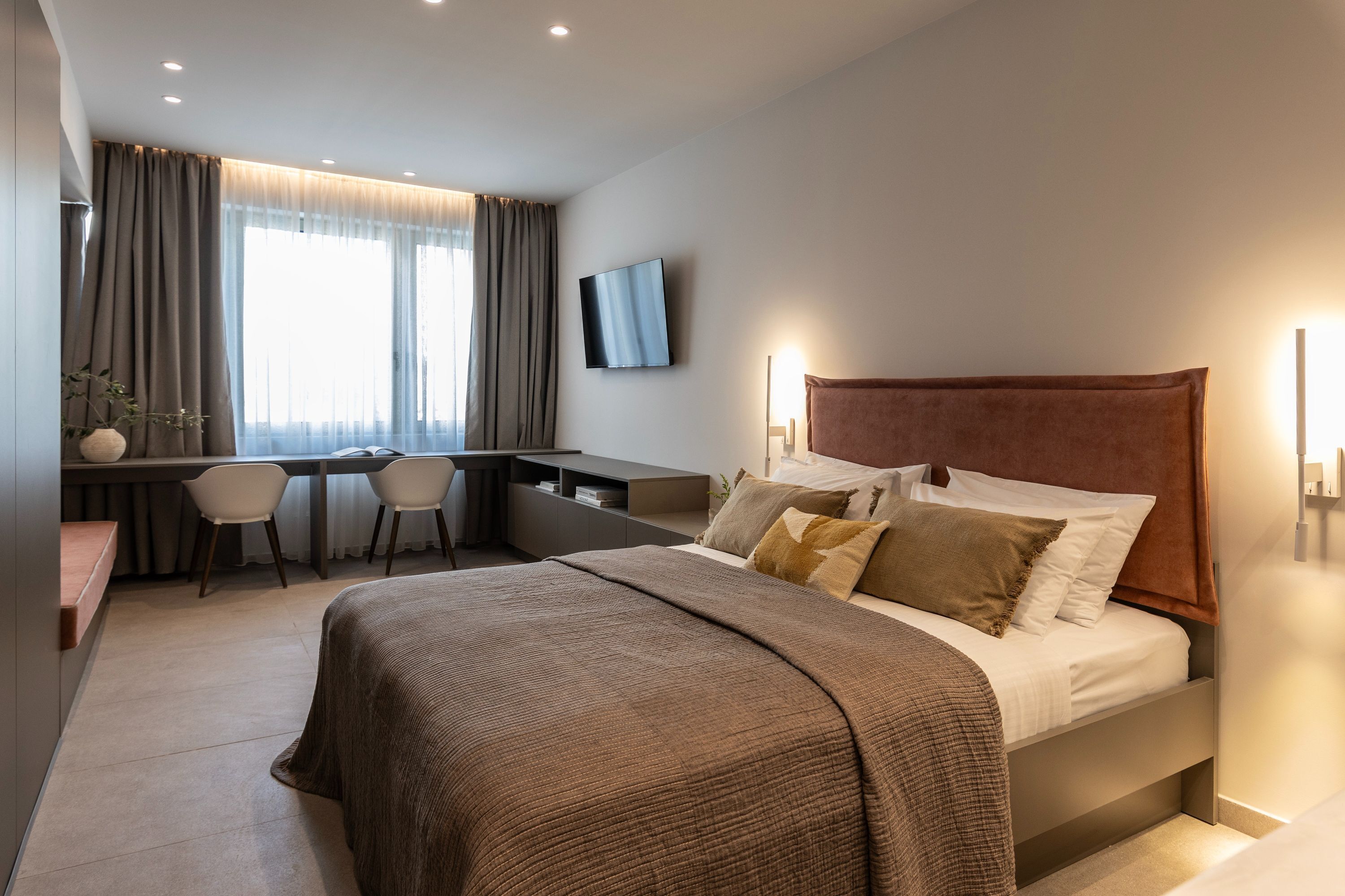 Una habitación de hotel moderna con una cama grande, un escritorio y un televisor.